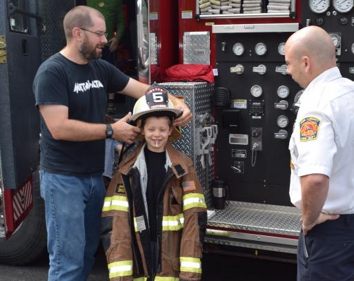 How does that fit? A youngster tries on a fireman’s hat and coat.