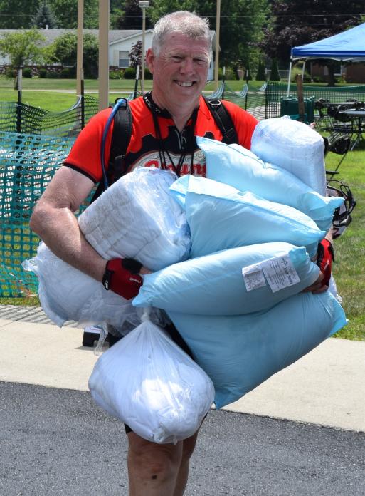 David Carse carries pillows and bedding to his sleep area. This was his 10th ride, raising $1,045 for charity this year.